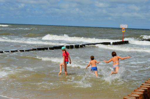 Free Stock Photo of Children playing in a stormy sea near the breakwater. Baltic Sea
