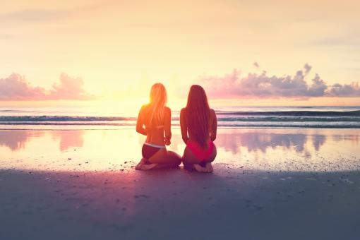 Free Stock Photo of Two Young Women Watching the Sunset Over the Ocean