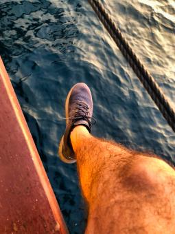 Free Stock Photo of Hanging legs and feet of a man on a boat