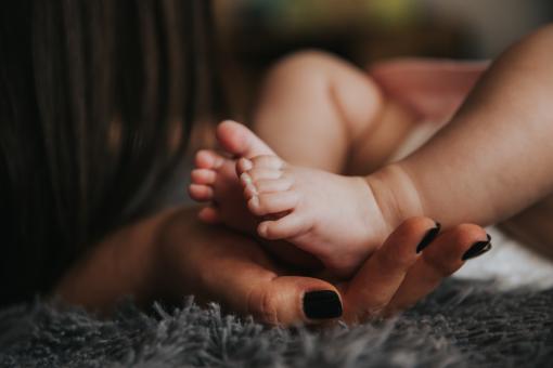 Mothers Hand on Child's Feet - Free Stock Photo