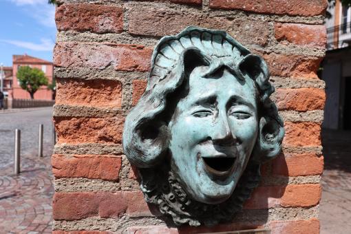 Bronze sculpture on a brick wall of woman laughing - Free Stock Photo