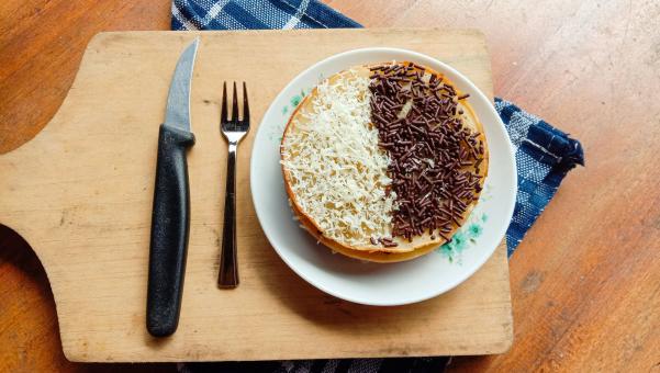 A photo of someone eating a mini martabak and drinking a cup of 