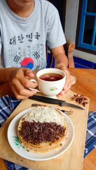 A photo of someone eating a mini martabak and drinking a cup of 