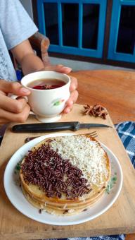 A photo of someone eating a mini martabak and drinking a cup of 
