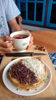 A photo of someone eating a mini martabak and drinking a cup of 