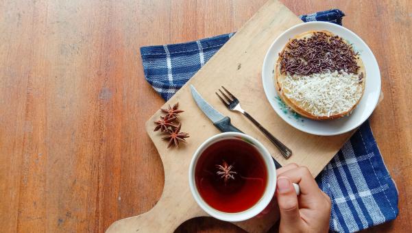 A photo of someone eating a mini martabak and drinking a cup of 