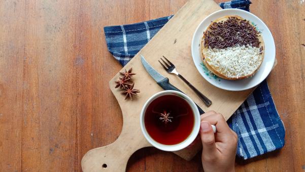 A photo of someone eating a mini martabak and drinking a cup of 